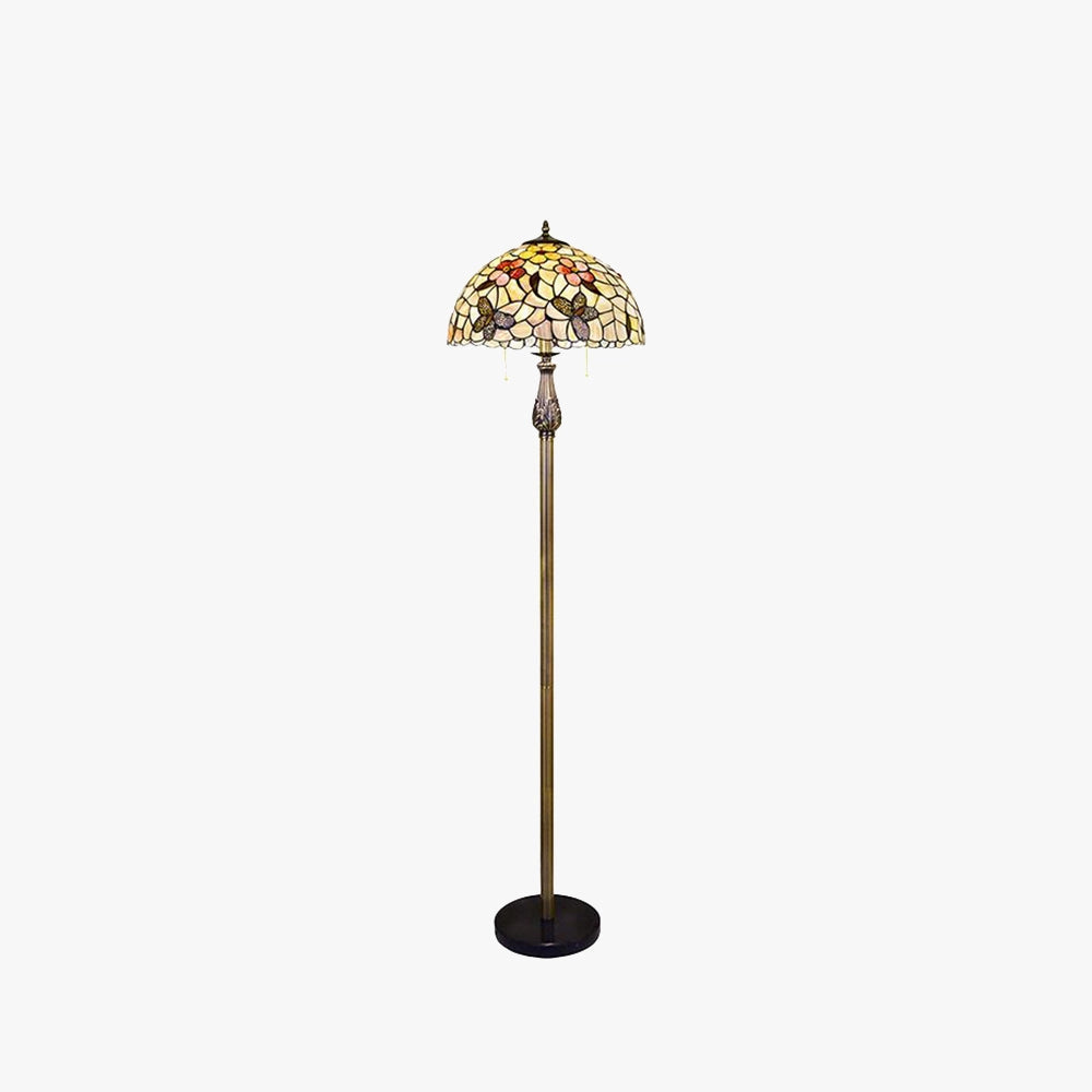 Tiffany-style floor lamp with a dragonfly stained glass shade and a brass pole, set against a backdrop highlighting its intricate design.