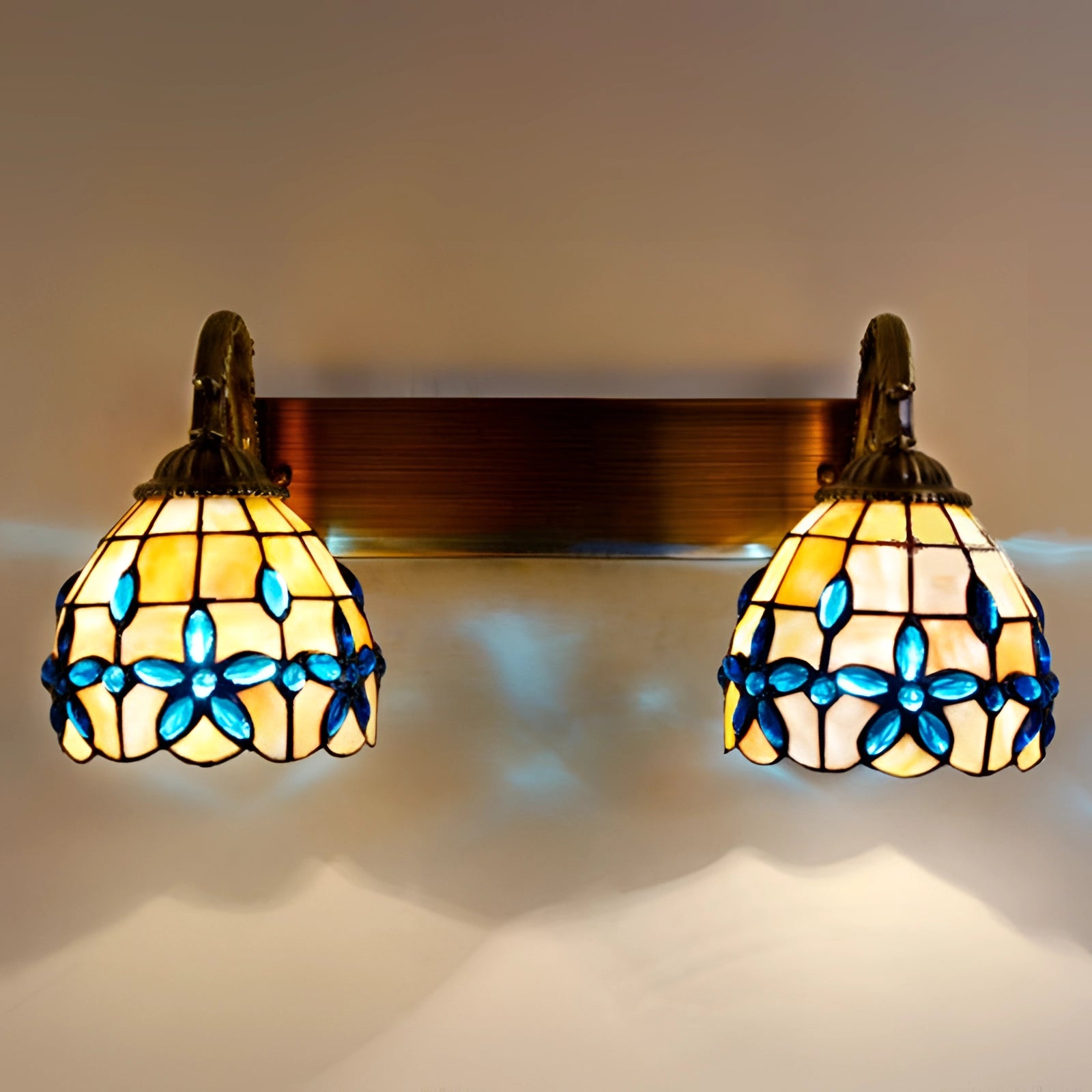 Tiffany-style vintage flower wall lamp with stained glass design featuring amber and orange hues, mounted on a wooden fixture, showcasing a symmetrical artistic pattern.