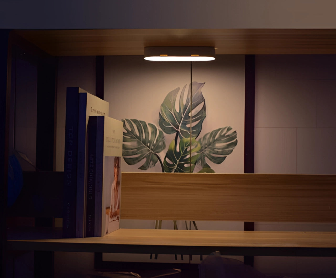 Compact USB LED wireless motion sensor lamp placed on a wooden surface in a modern interior setting with minimalist decor and green plants.
