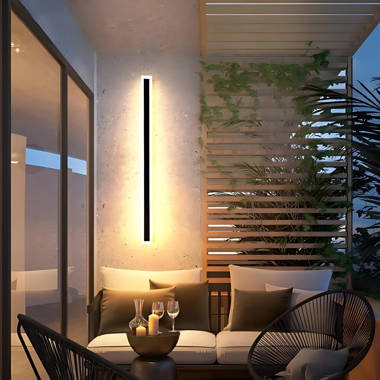 Vertical LED wall light mounted on an exterior wooden wall, illuminating a minimalist outdoor balcony area with modern furniture, including chairs and a table, showcasing a blend of contemporary architecture and design.