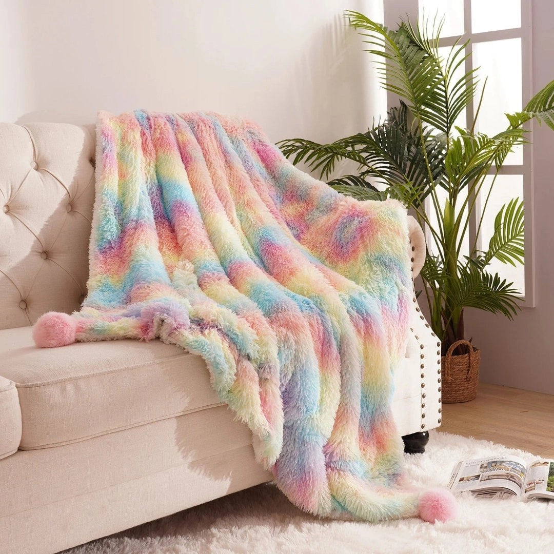 Vibrant multicolor faux fur blanket with soft pastel hues draped over a studio couch in a cozy living room setting, surrounded by houseplants in flowerpots on a wooden floor.