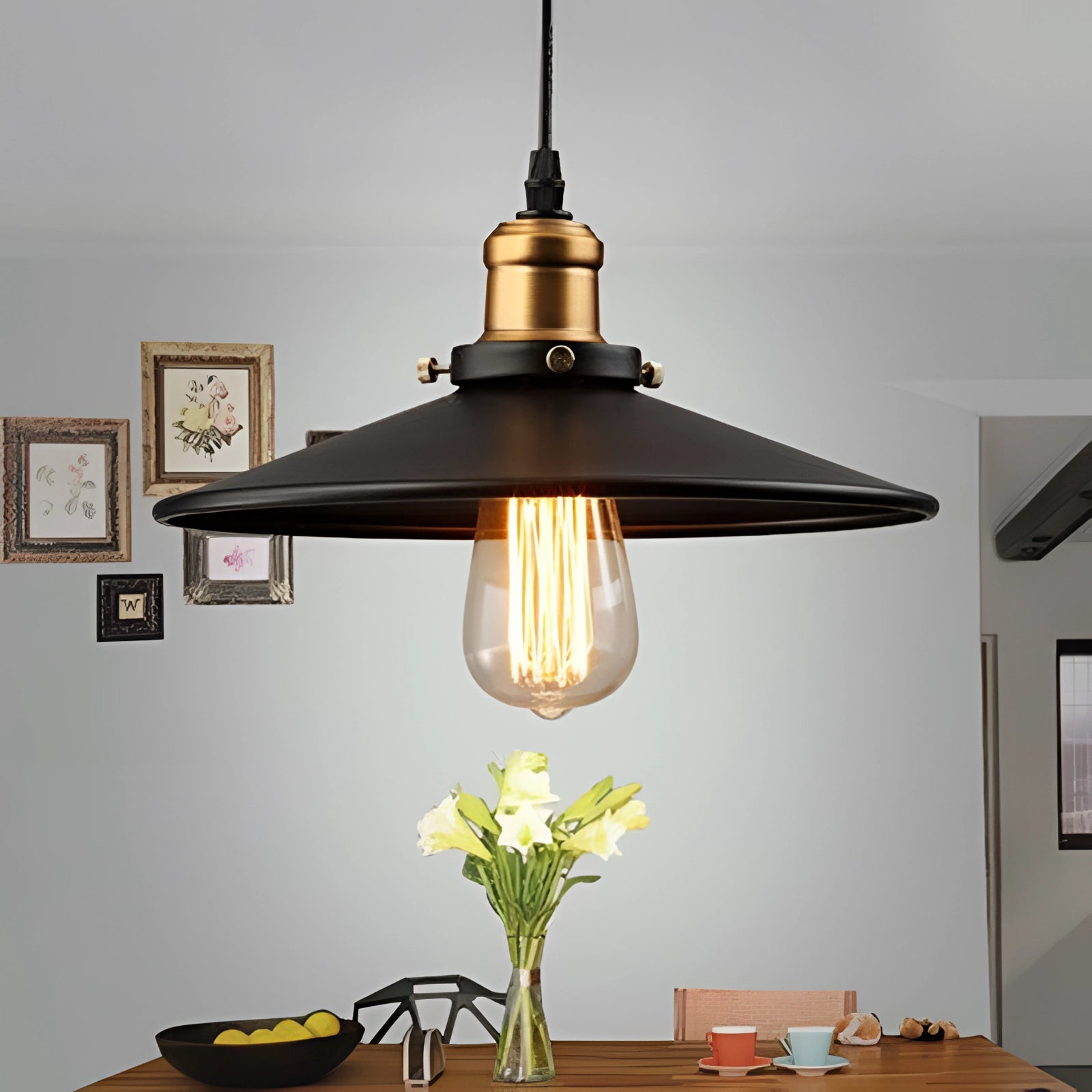 Vintage black Edison bulb pendant light with industrial metallic dome, 14.2 inches in size, hanging above a wooden table. The light fixture is prominently featured in a stylish interior design setting with a picture frame on the wall, and a small plant adding a touch of greenery.