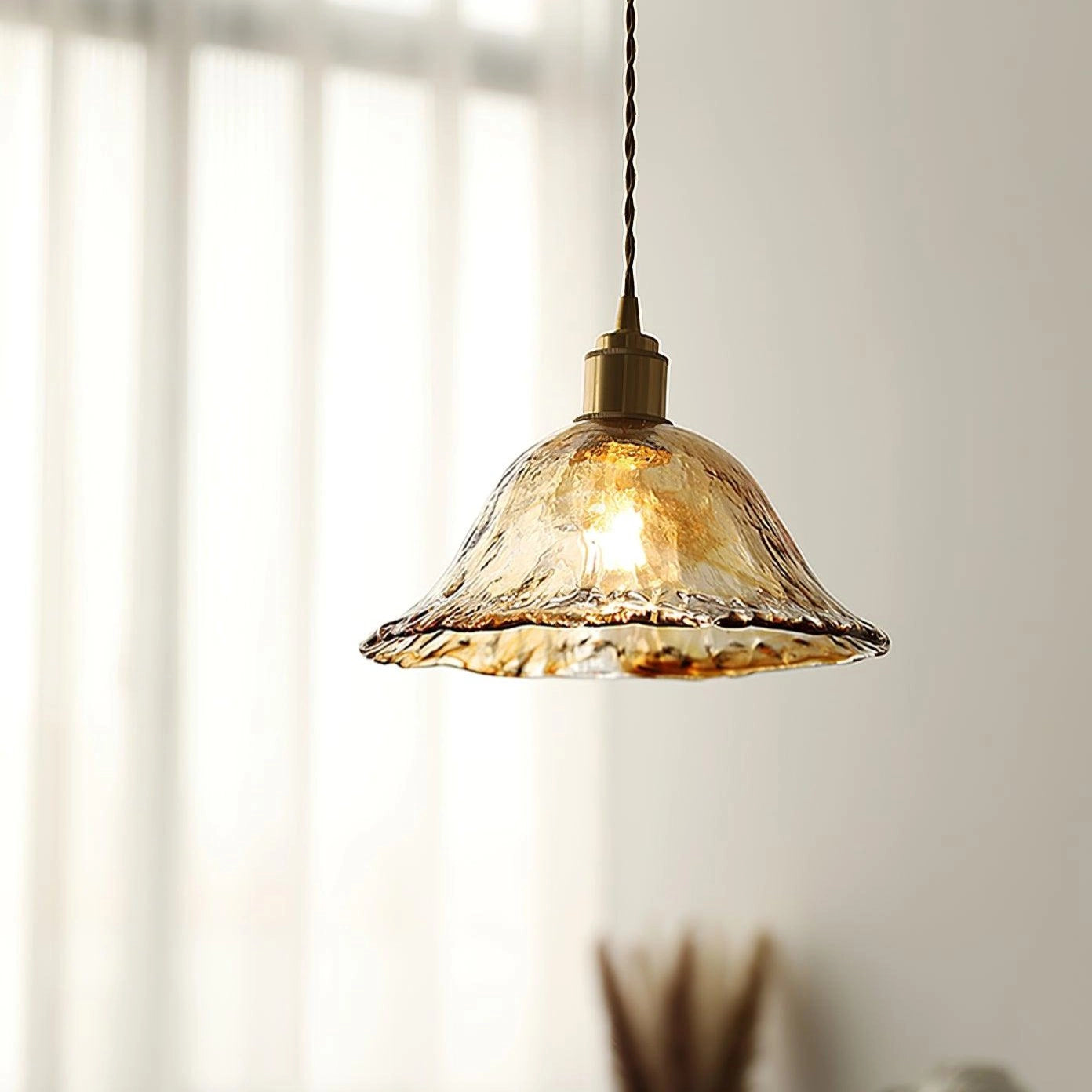 Vintage brass glass pendant light with a retro floral design, featuring amber-tinted glass and metal detailing, suspended from a ceiling fixture.