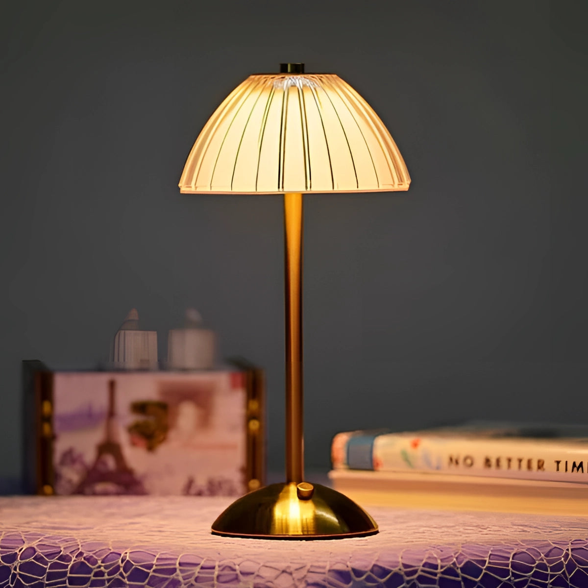 Vintage brass table lamp featuring a pleated shade in a mid-century modern design, illuminating a cozy space, with a wooden base and books nearby.