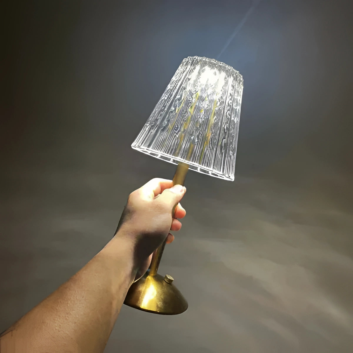 A vintage brass table lamp with a pleated shade, showcasing a mid-century modern design. The lamp features a sleek metal base and a stylish fabric shade, emitting a warm and inviting glow. The design is elegant and complements various interior styles.