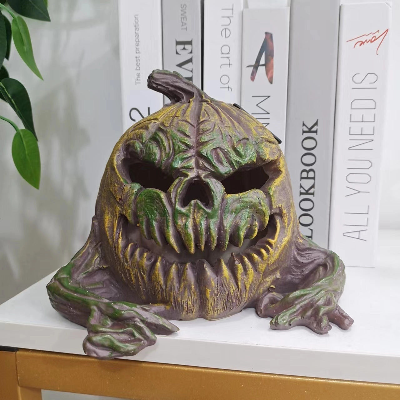 A vintage bronze Halloween pumpkin sculpture featuring a spooky design with exaggerated facial features, suitable as a table centerpiece.
