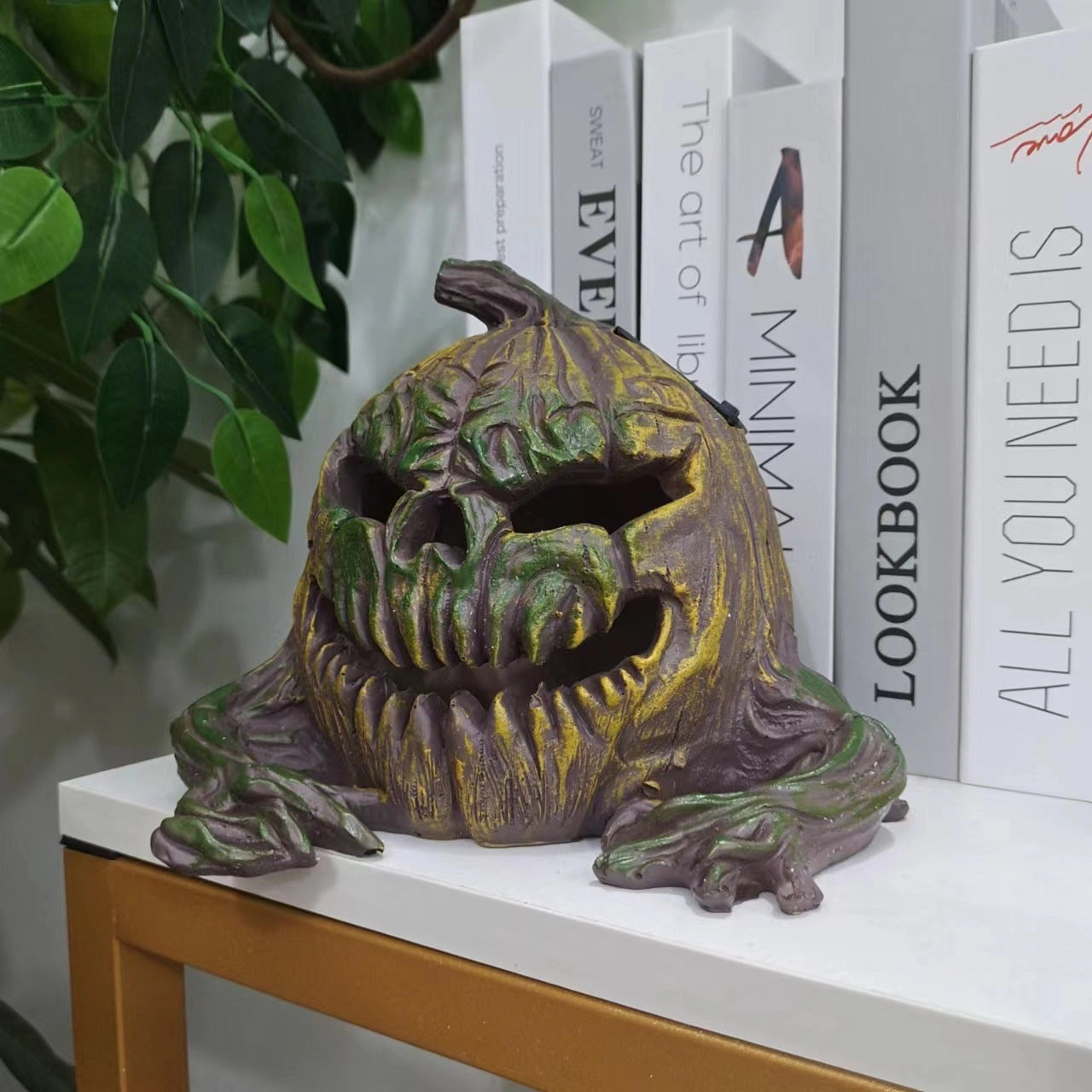 Vintage bronze Halloween pumpkin sculpture featuring a spooky design, ideal as a table centerpiece. The artistic piece shows intricate details and a metallic finish, combining elements of creative arts with cryptid-inspired features.