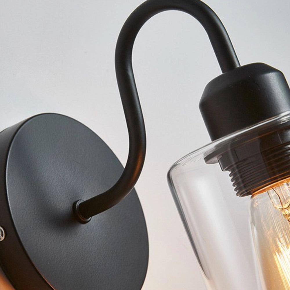 A vintage Edison bulb wall sconce with a black metal frame and clear glass shade, showcasing its elegant design and industrial style.