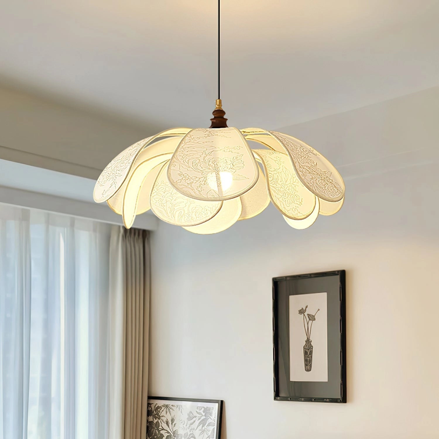 Vintage floral pendant light with etched glass lampshade hanging from the ceiling in a dining room with wooden accents and a window with curtains.