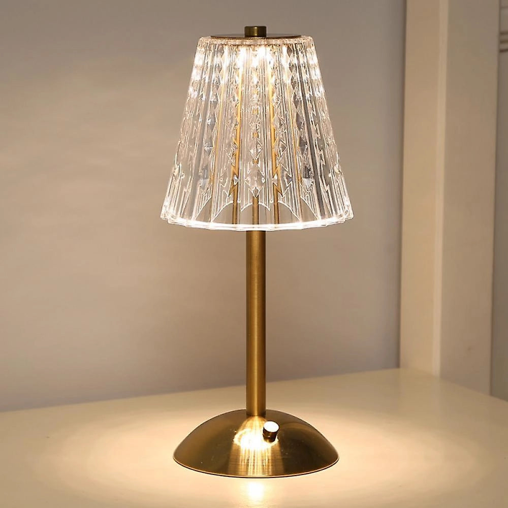 Vintage gold base table lamp with a pleated lampshade, providing soft lighting; features a blend of metal and wood elements, showcasing an artistic and elegant design.