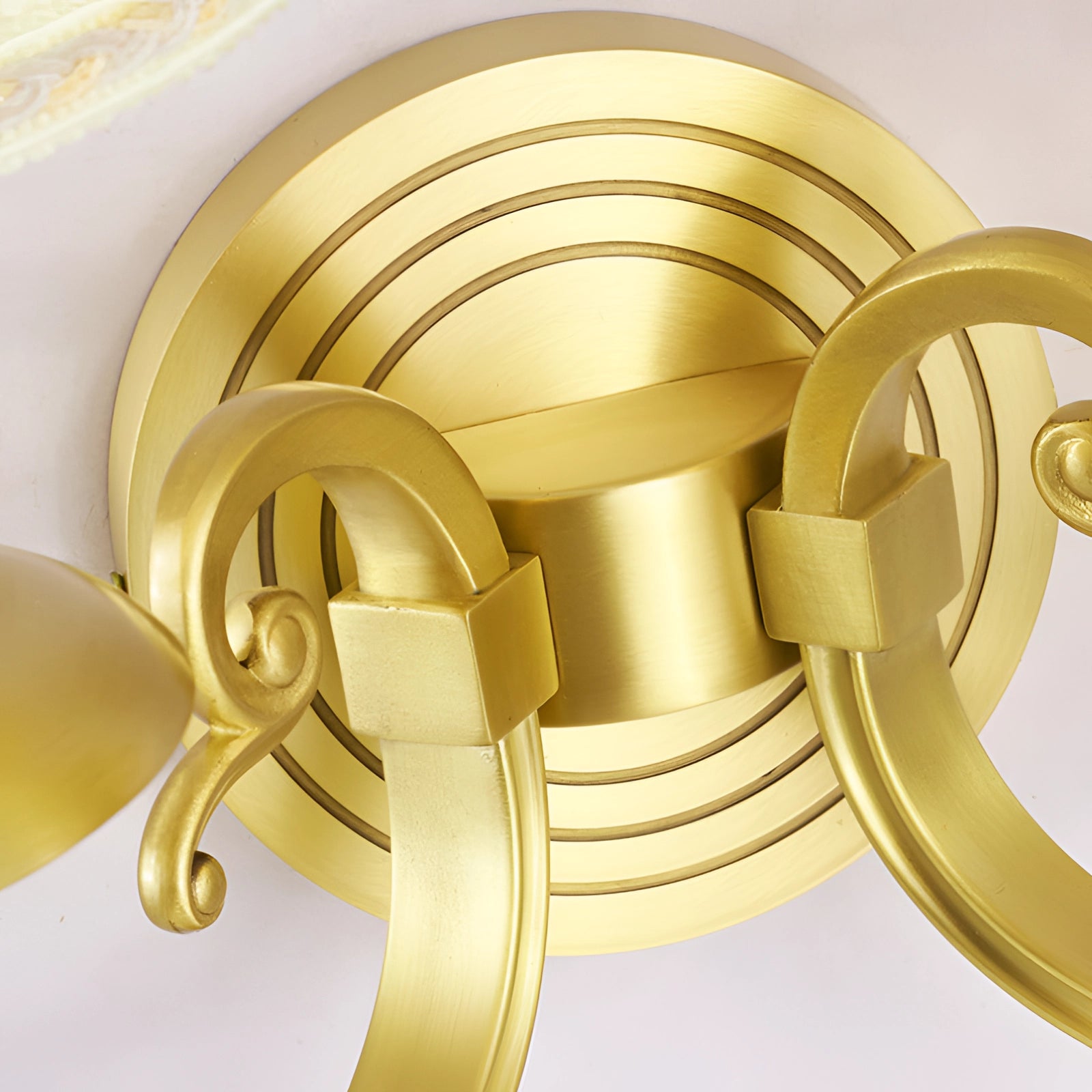 Vintage gold wall sconce featuring a brass finish with an amber hue, showcasing a circular symmetrical design and intricate patterns, resembling art and jewelry elements.
