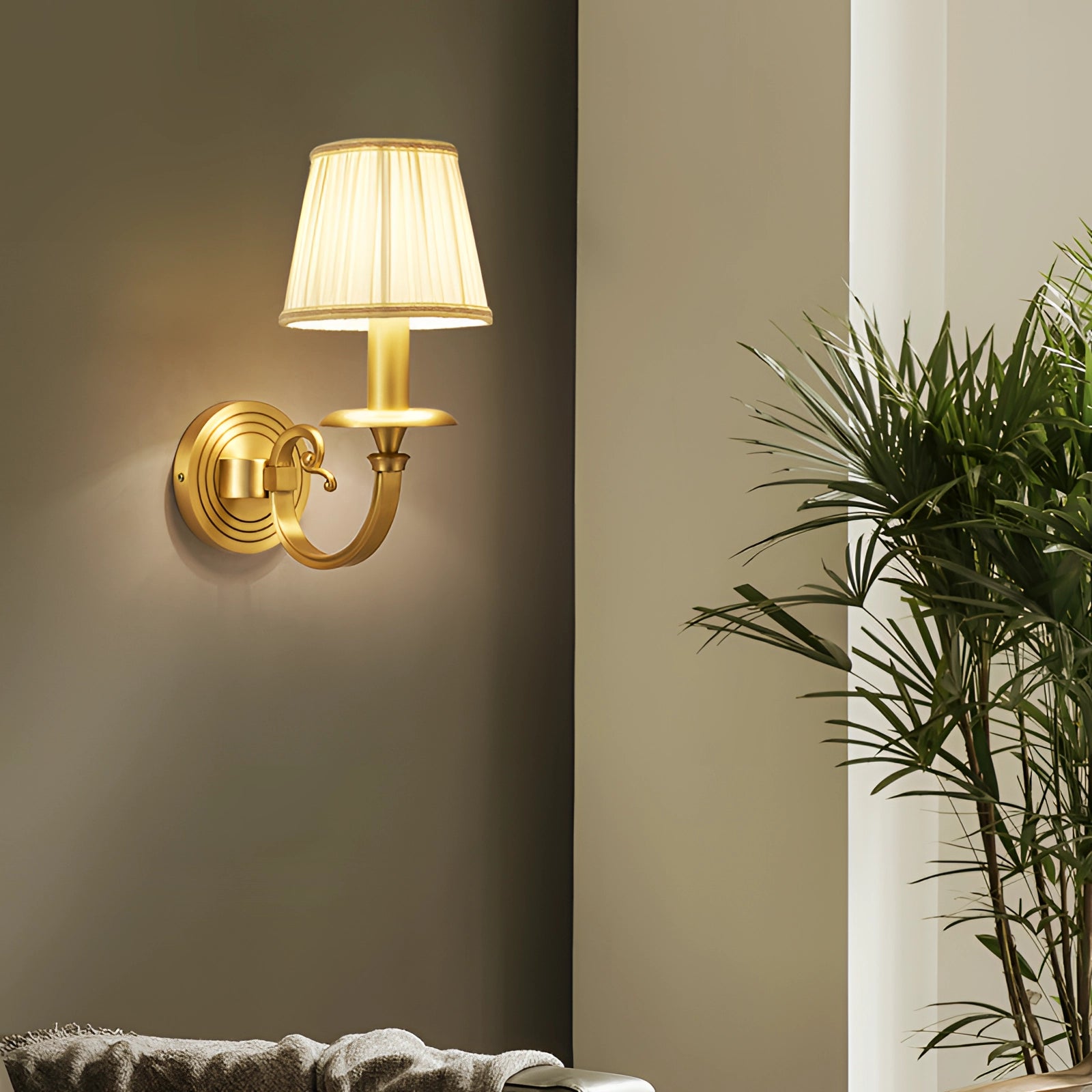 Vintage gold wall sconce made of brass, mounted on a rectangular wooden base, designed for indoor lighting. The fixture is styled with a classic look, complementing interior design elements and casting warm light onto nearby plants.
