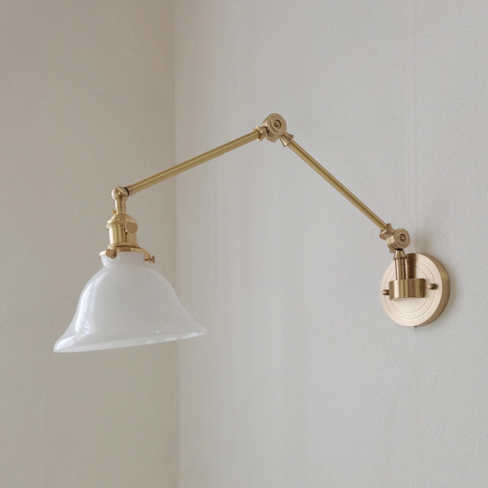 Vintage green enamel wall lamp with brass arm, featuring a white lampshade and a circular design, mounted on a wooden wall, showcasing a blend of metal elements and classic interior design aesthetics.