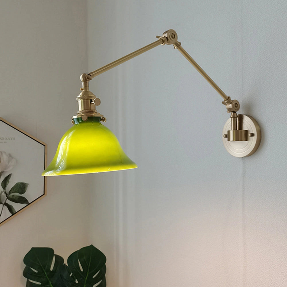 Vintage green enamel wall lamp with brass arm, featuring a round metal lampshade and a sleek brass fixture, mounted on a wooden wall.