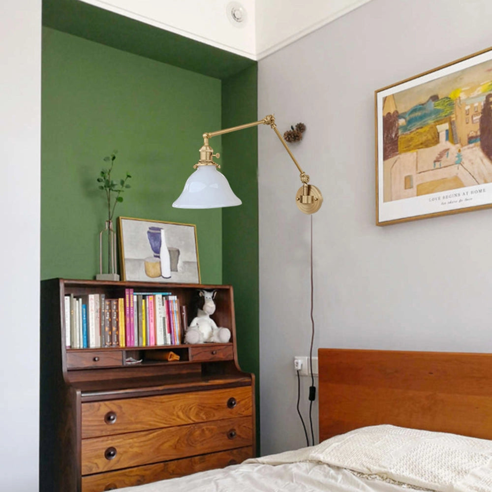 Vintage green enamel wall lamp with brass arm mounted on a wall, set against a backdrop of wooden cabinetry and interior design elements.