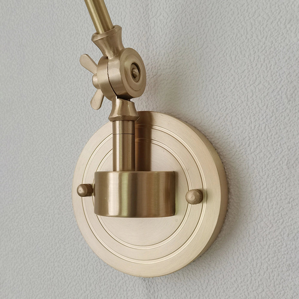 Vintage green enamel wall lamp featuring a brass arm, mounted on a wooden surface in a home setting.