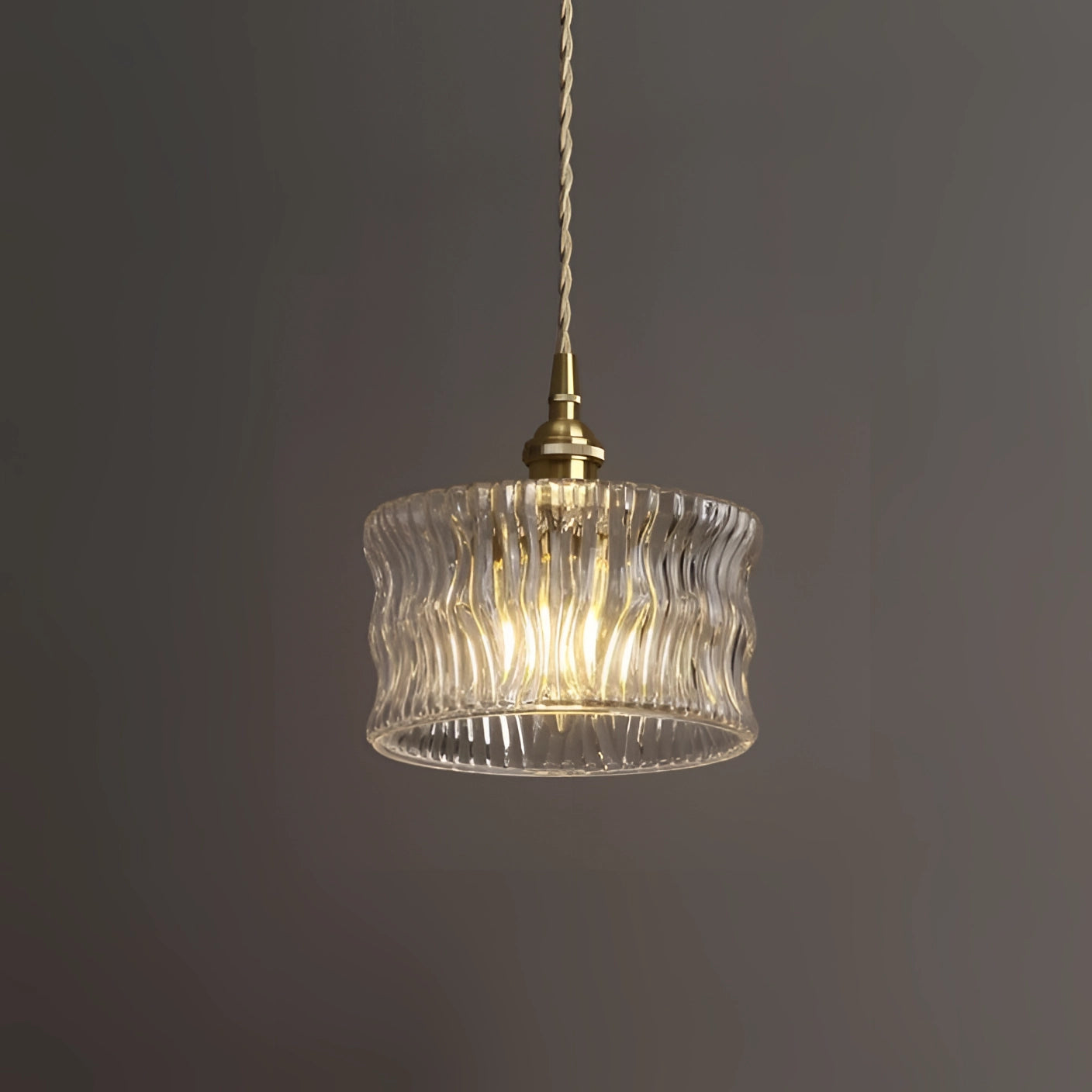 Vintage green glass pendant light with industrial brass fixture, hanging from ceiling, featuring clear waves design.