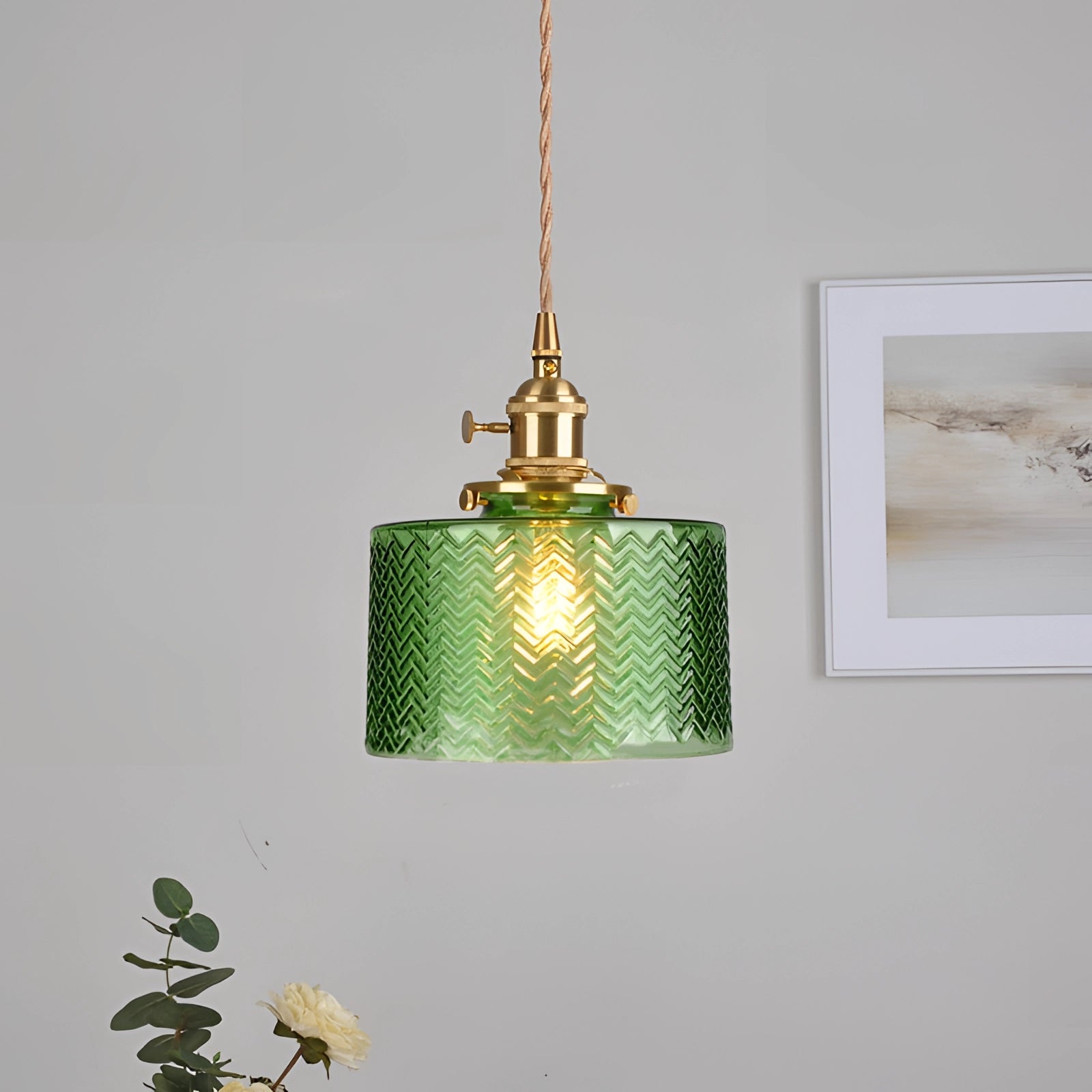 Vintage industrial green glass pendant light with brass fittings hanging indoors.