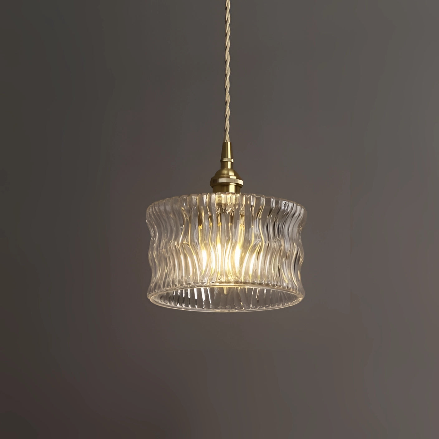 Vintage industrial glass pendant light with green shade and brass fittings, featuring a clear wave pattern, hanging from the ceiling.