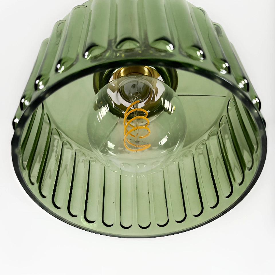 Vintage industrial glass pendant light with green shade and brass fittings hanging from the ceiling.
