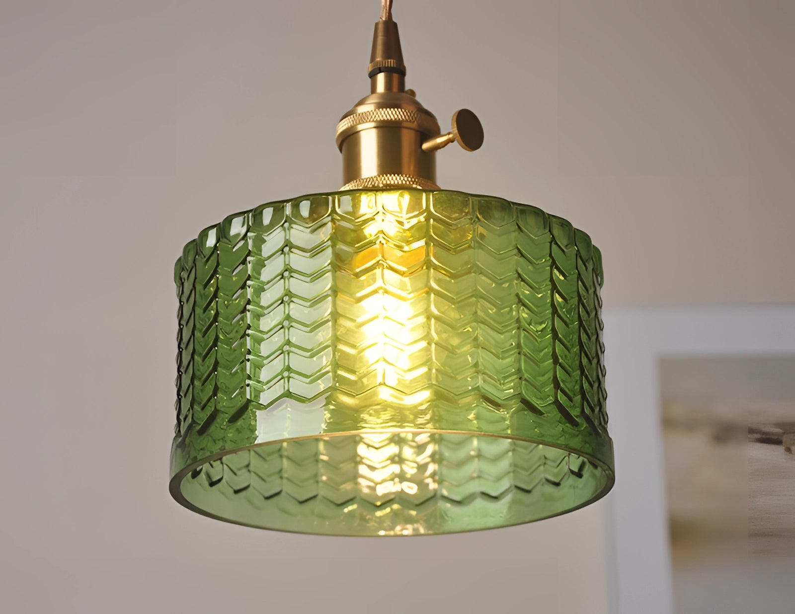 Vintage industrial glass pendant light with green shade and brass fittings hanging from the ceiling.