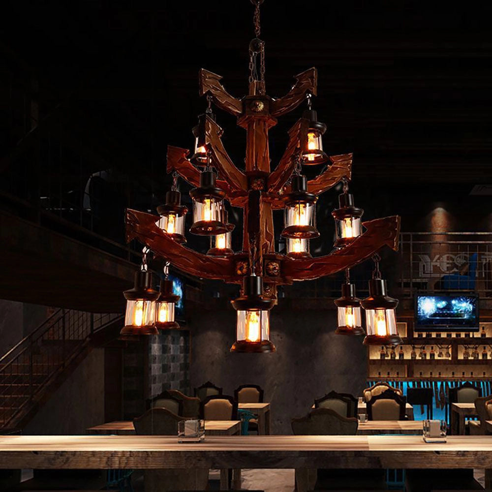 Vintage nautical ship wheel chandelier with rustic maritime design, featuring elegant lighting elements in a dark setting.