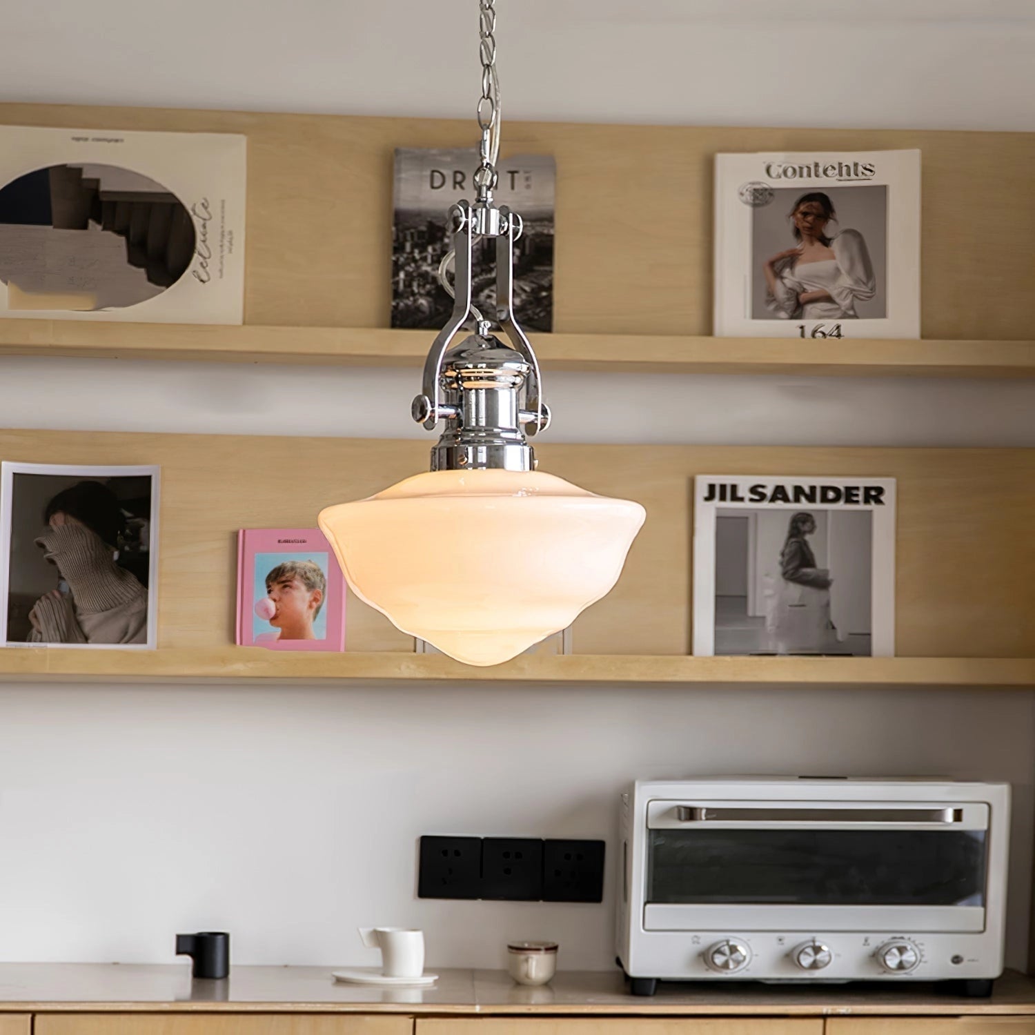 Vintage pendant light with an industrial retro design featuring a glass shade, hanging from a ceiling in a stylish interior setting. The lamp is surrounded by cabinetry and shelving, contributing to the art deco aesthetic of the room.