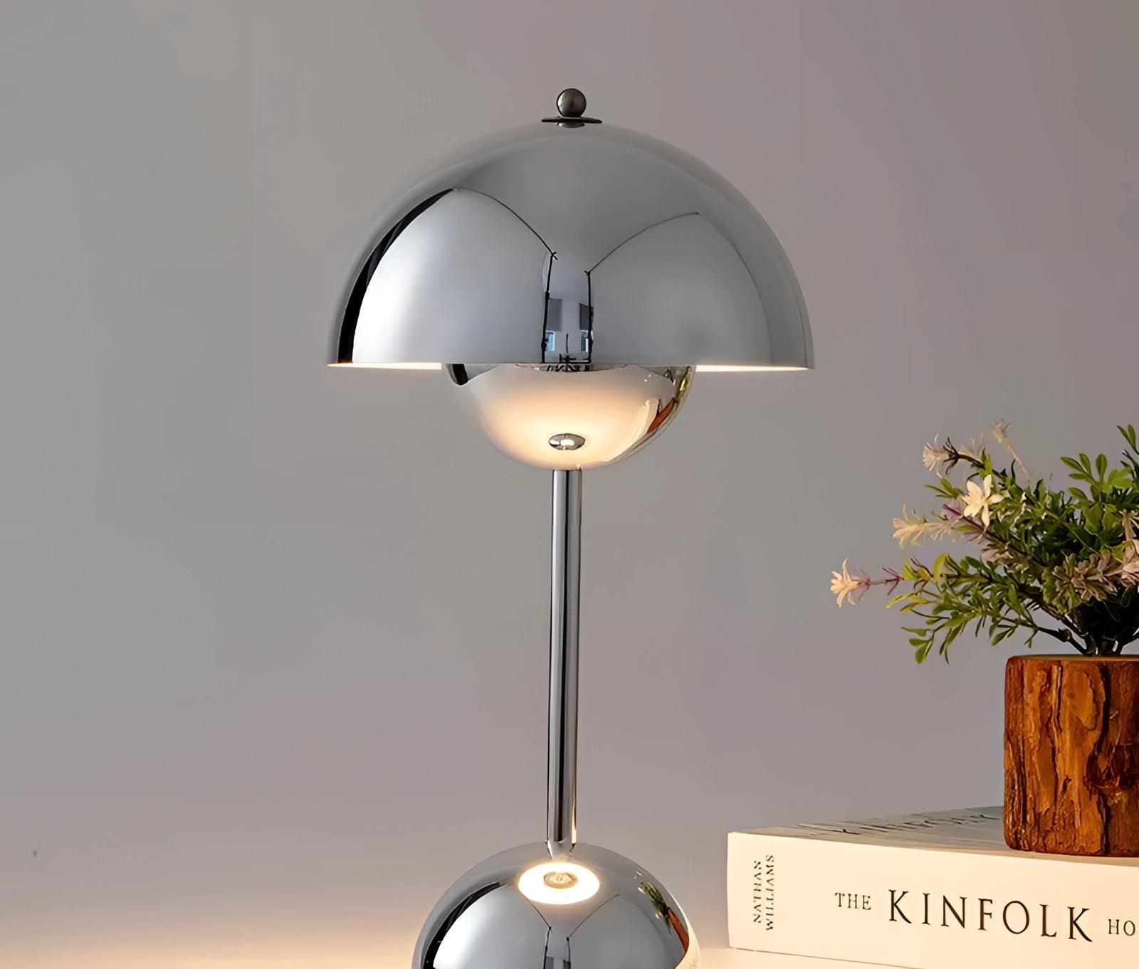 Vintage red desk lamp with a retro design, featuring a wooden base and a chromed finish, placed beside a small potted plant.