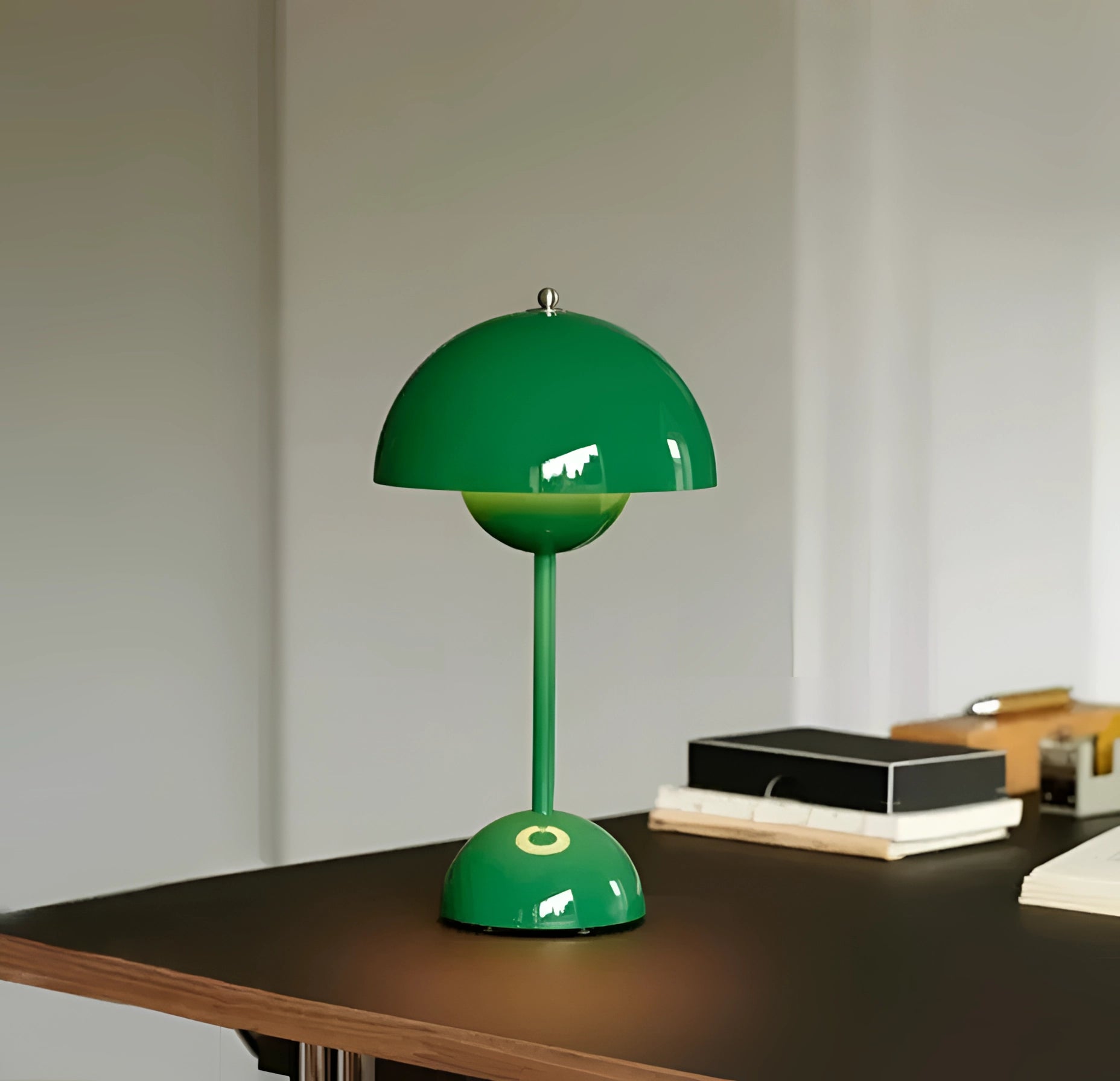 A vintage red desk lamp with a retro design, featuring a wooden base, displayed on a desk alongside a clock and shelving.