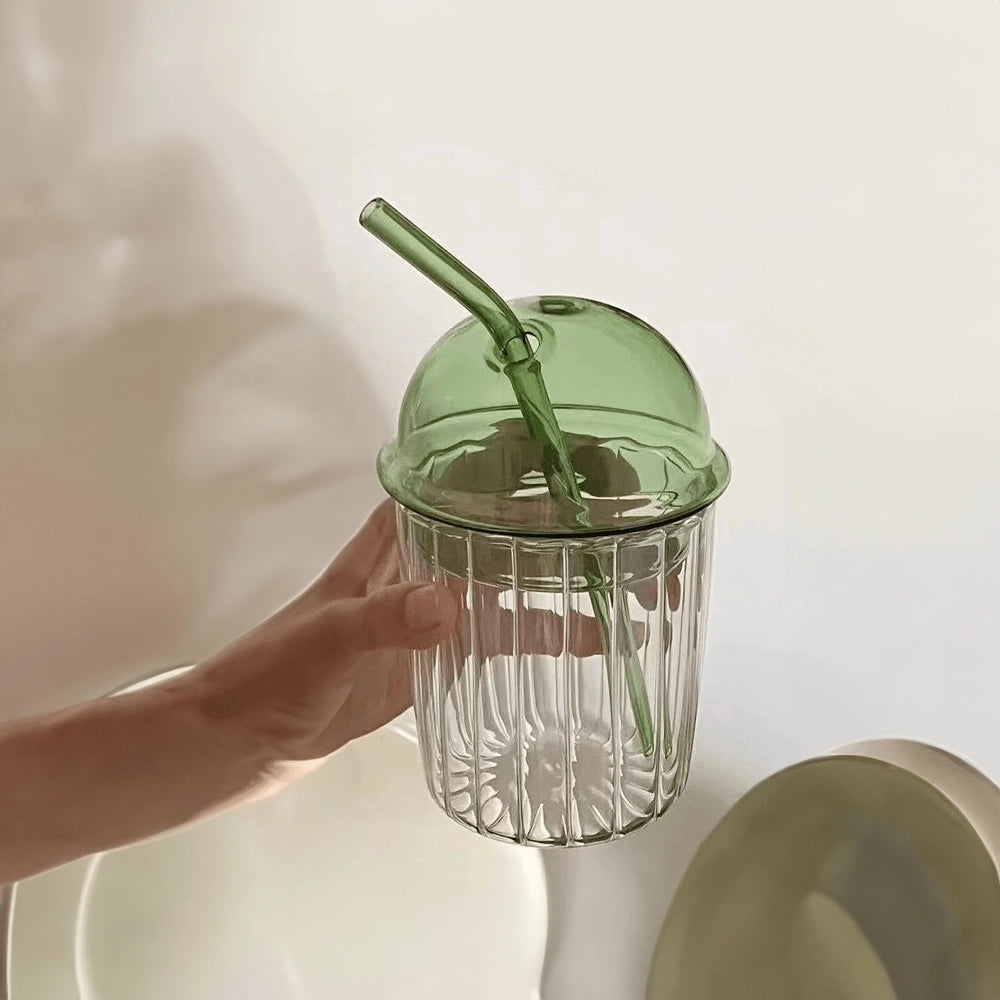 Vintage-style green glass cup with lid and straw, eco-friendly design.