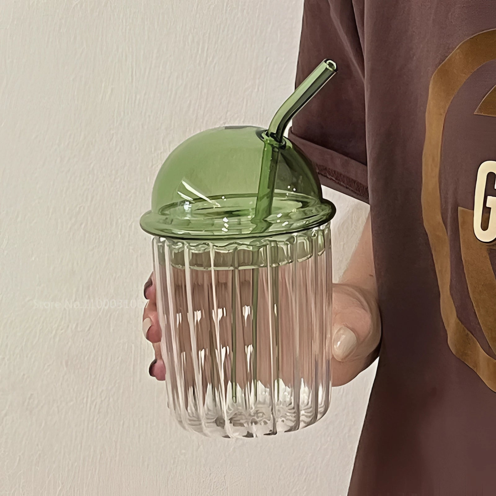 Vintage-style green glass cup with a lid and straw, showcasing an eco-friendly design.