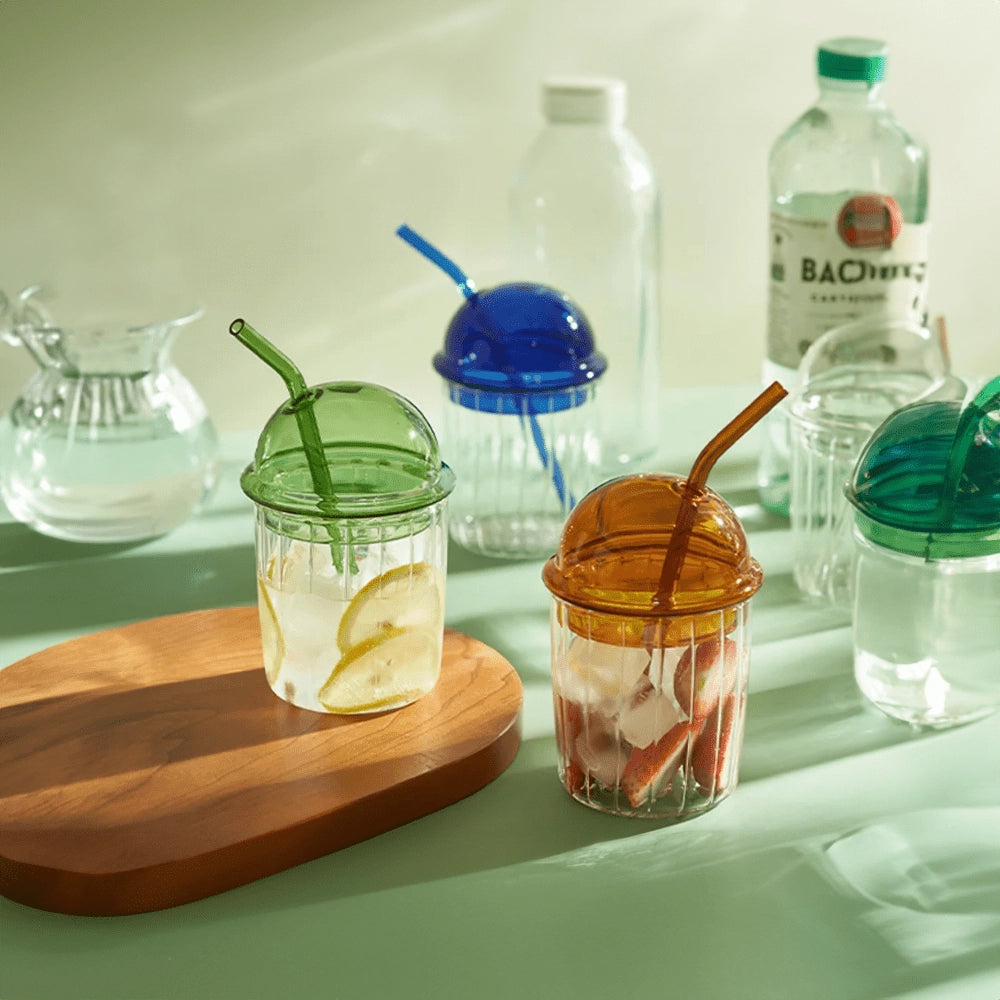 Vintage-style green glass cup with a lid and straw, featuring an eco-friendly design.