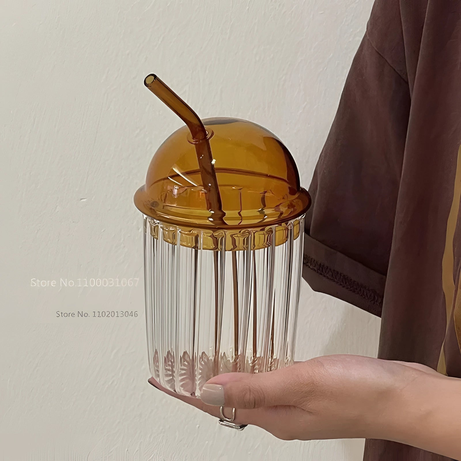 Vintage-style green glass cup with a lid and straw on a table, showcasing its eco-friendly design.