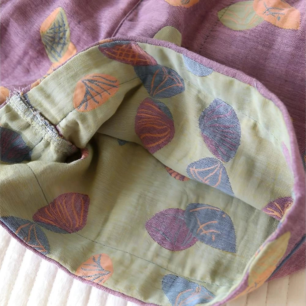 Women's colorful leaf print summer shorts with an elastic waist, featuring a mix of brown, purple, pink, and beige hues in a circular pattern.