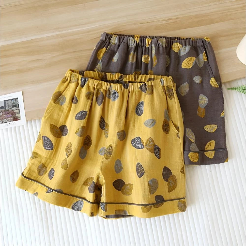 Colorful women's summer shorts with a leaf print and an elastic waistband, hanging on a clothes hanger.