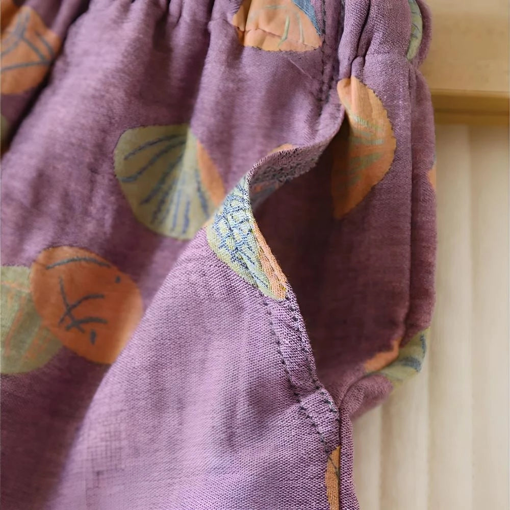 Colorful women's summer shorts with a vibrant leaf print design, featuring shades of purple, pink, and magenta. Made from a breathable textile material, the shorts have an elastic waistband for comfort and style.