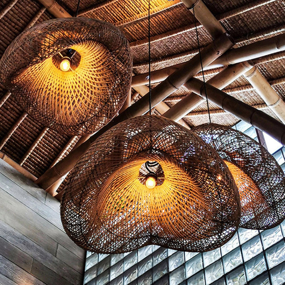 Eco-friendly woven rattan pendant light with amber glow, featuring a symmetrical boho design, hanging from a ceiling in a stylish interior setting.