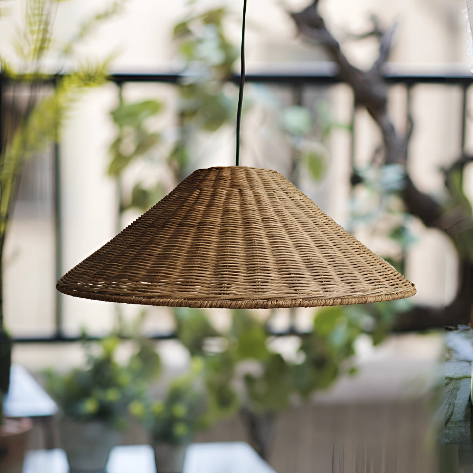 Eco-friendly woven rattan conical pendant light hanging in a Scandinavian-themed room with wooden elements, large windows, and indoor plants.