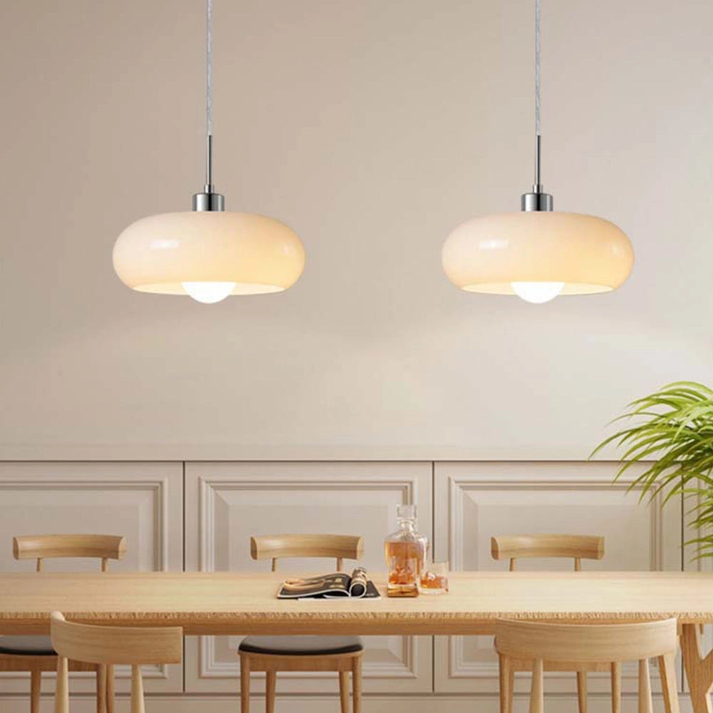A modern Scandinavian ceiling lamp featuring a yellow elliptical pendant light, hanging above a wooden table within a stylishly designed interior space.