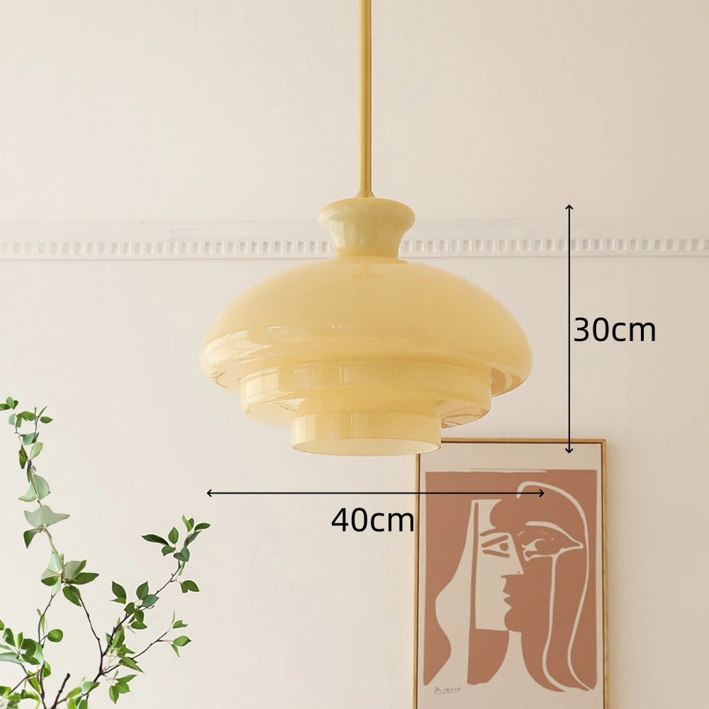 Modern Scandinavian minimalist yellow pendant light fixture hanging from the ceiling, with a sleek design and surrounded by minimal decor including a plant and abstract art.