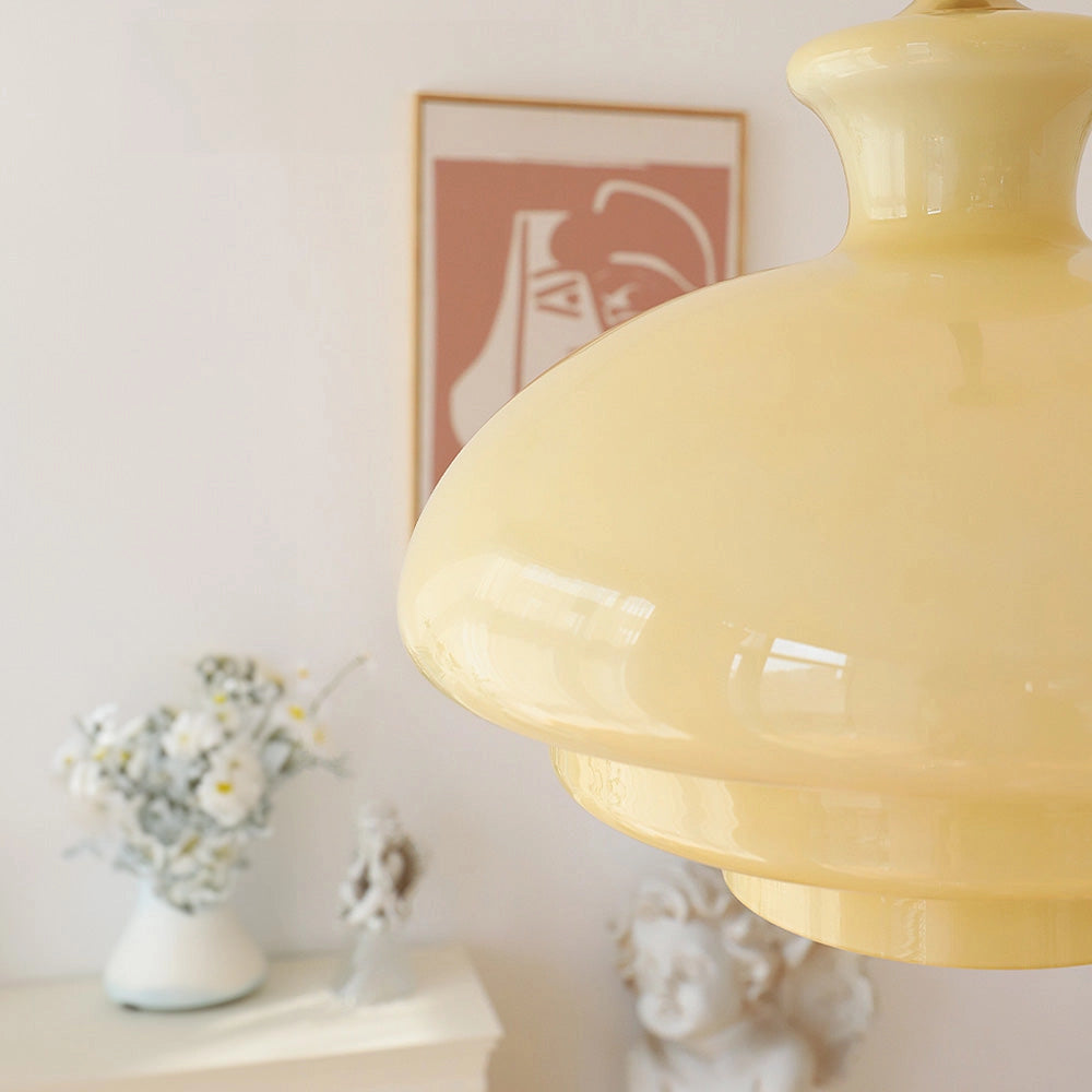 Modern Scandinavian minimalist yellow pendant light hanging from ceiling, illuminating a stylish interior space with a vase of flowers on a wooden table.